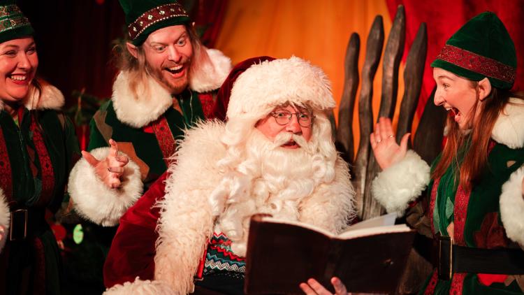 Father Christmas reading a book with his Elves