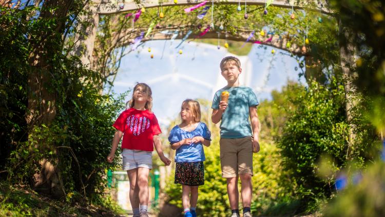 Children walking underneath an archway and hanging eggs at the Eden Project