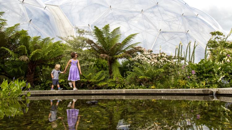 Two children exploring the Outdoor Gardens with Biome in background