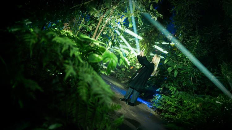 Girl with blonde hair in the Rainforest Biome taking a selfie amongst the Christmas lights
